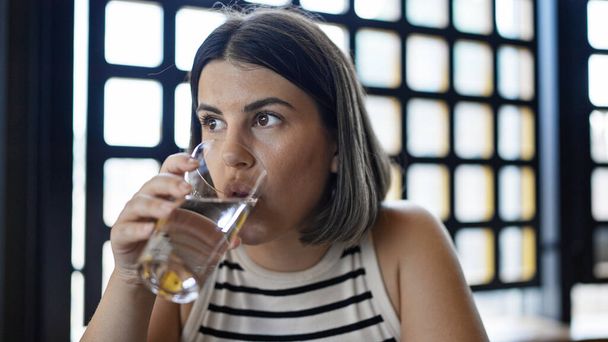 Genç ve güzel İspanyol kadın restoranda bir bardak su içiyor. - Fotoğraf, Görsel