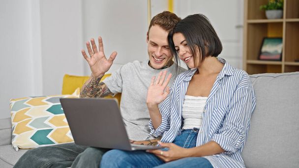 Beautiful couple sitting on sofa together having video call at home - Photo, Image