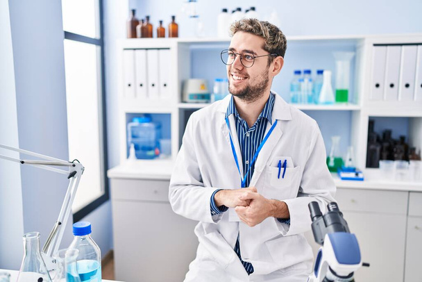 Молодой человек ученый улыбается уверенно выступая в лаборатории - Фото, изображение