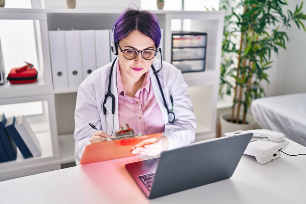 Νεαρή όμορφη συν μέγεθος γυναίκα γιατρός γράφει στο έγγραφο έχοντας τηλεδιαβούλευση στην κλινική - Φωτογραφία, εικόνα
