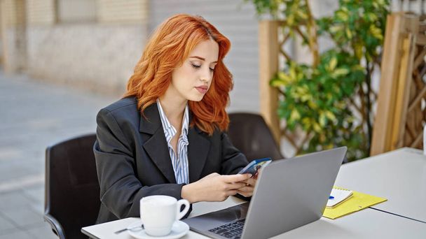Jeune rousse femme d'affaires utilisant un smartphone sur la terrasse du café - Photo, image