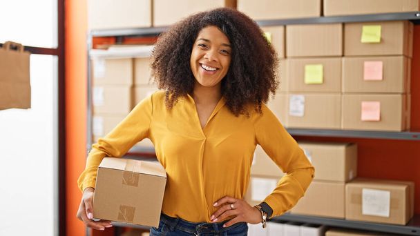 African american woman ecommerce business worker holding package smiling at office - Valokuva, kuva