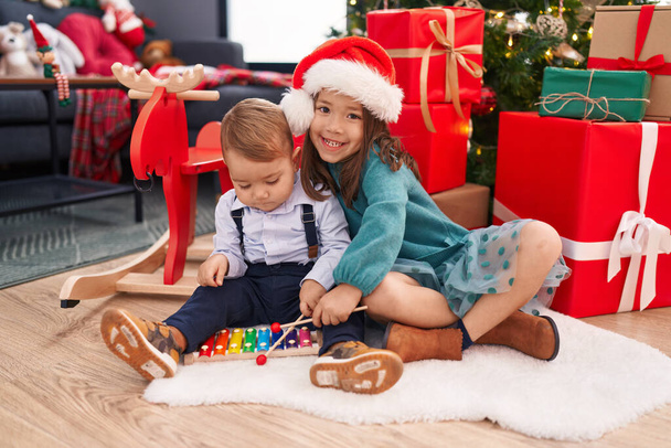 Imádnivaló fiú és lány xilofonozik ünneplő karácsony otthon - Fotó, kép