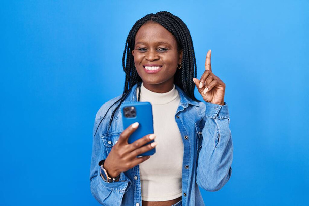 Afrikai nő fonat segítségével okostelefon gépelés üzenet meglepett egy ötlet vagy kérdés ujjal mutogató boldog arc, első számú  - Fotó, kép