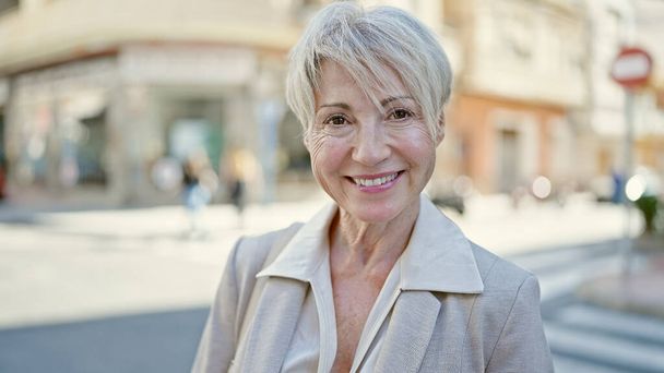 Moyen âge blonde femme souriante confiante debout dans la rue - Photo, image