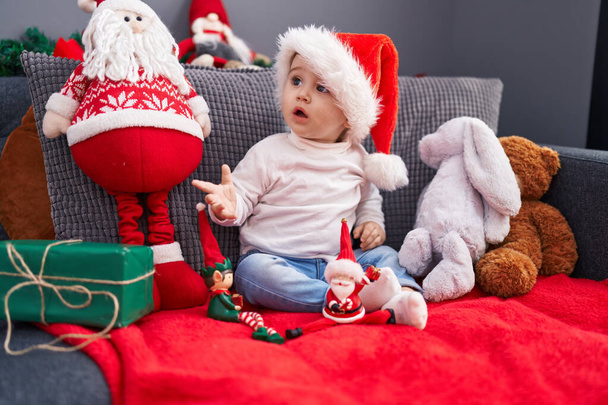Adorável bebê caucasiano sentado no sofá com decoração de Natal em casa - Foto, Imagem