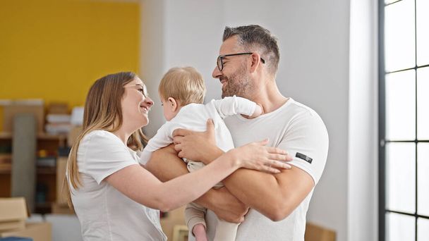 Äidin, isän ja vauvan perhe hymyilee yhdessä uudessa kodissa - Valokuva, kuva