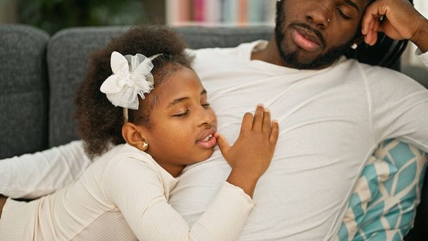 Αφρο-αμερικανός πατέρας και κόρη ξαπλωμένοι στον καναπέ και κοιμούνται στο σπίτι - Φωτογραφία, εικόνα