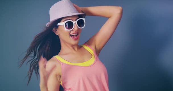 Woman, hat and sunglasses in studio photoshoot, wind and smile for light, paparazzi and blue background. Fashion model, celebrity girl and flash photography for style, excited and happy for clothes. - Footage, Video