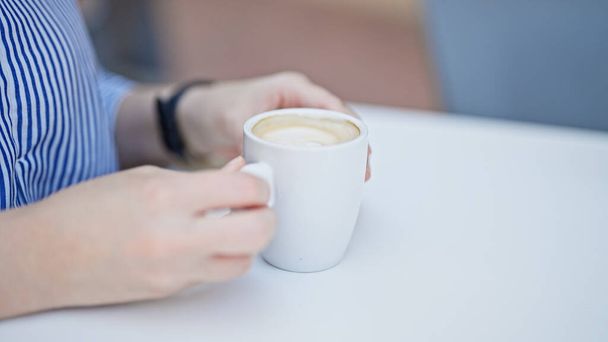 Jovem bela mulher hispânica segurando xícara de café sentado na mesa no terraço do café - Foto, Imagem