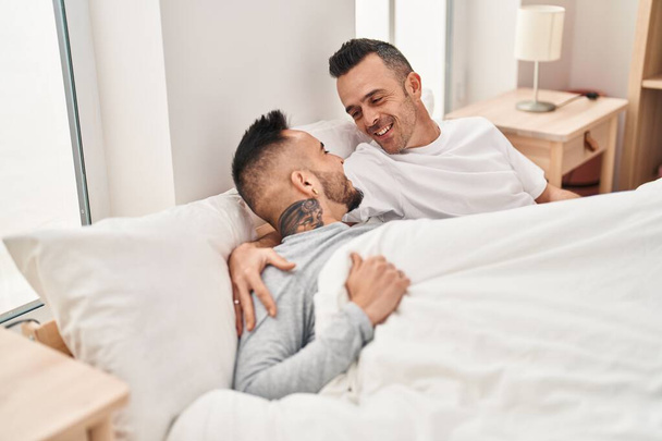 Dos hombres en pareja acostados en la cama abrazándose en el dormitorio - Foto, imagen