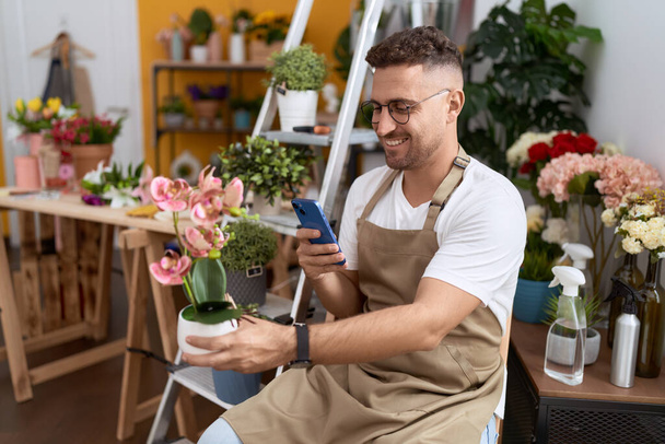 Jonge Spaanse man bloemist maken foto te planten door smartphone bij de bloemenwinkel - Foto, afbeelding