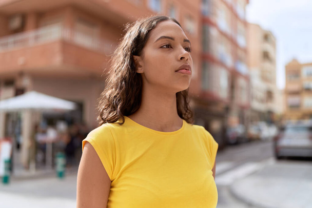 Молода афроамериканська жінка, яка дивиться на бік з серйозним виразом на вулиці. - Фото, зображення
