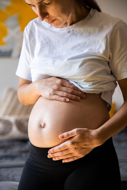 Mujer joven embarazada escuchando al bebé empujando sosteniendo su vientre. - Foto, imagen