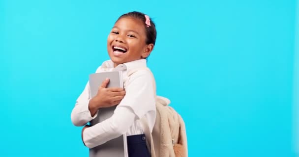 School, books and portrait of child excited for education or homework isolated in a studio blue background. Learning, development and kid or young girl happy in uniform holding textbook with a smile. - Footage, Video