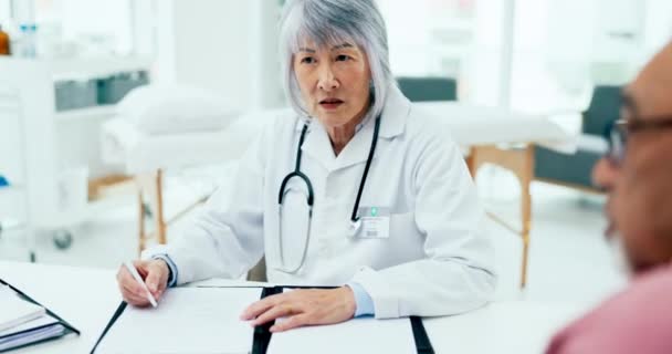 Doctor, woman and meeting couple with notes in clinic for assessment, test results or healthcare insurance. Mature asian therapist consulting patients for documents, medical history or surgery advice. - Footage, Video