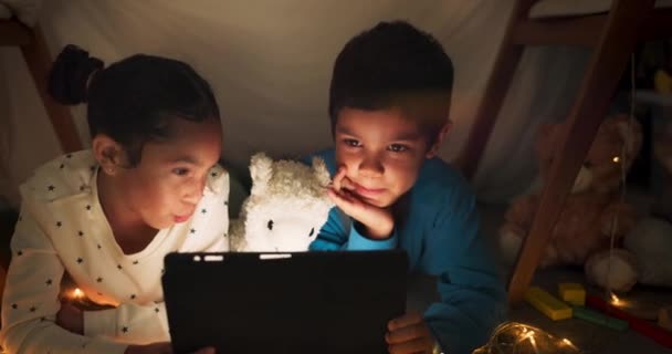 Night, tablet and children streaming in a tent house talking about internet video, show or movie online at night. Dark, digital and siblings or kids relax with watching cartoon app in the evening. - Footage, Video