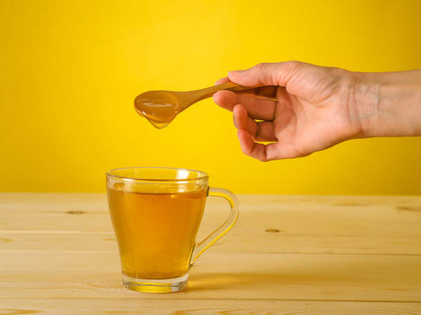 Miel tombant de cuillère dans un verre de thé au citron
 - Photo, image