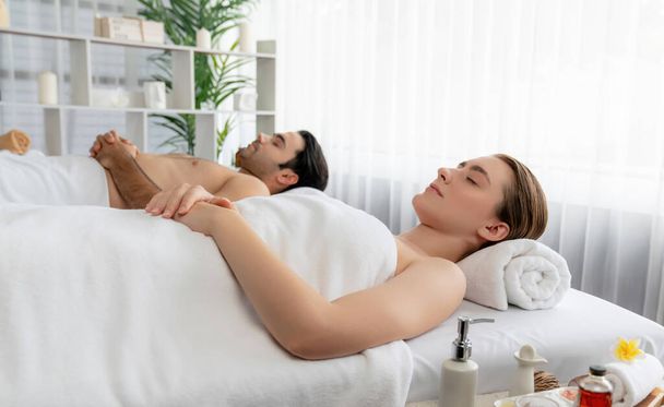 Caucasian couple customer enjoying relaxing anti-stress spa massage and pampering with beauty skin recreation leisure in day light ambient salon spa at luxury resort or hotel. Quiescent - Photo, Image