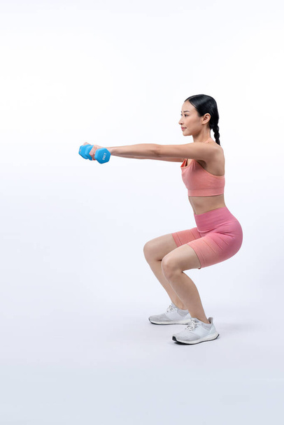 Energische, energische Frau beim Hantelheben auf isoliertem Hintergrund. Junge athletische asiatische Frau Kraft- und Ausdauertraining als Körpertraining-Routine. - Foto, Bild