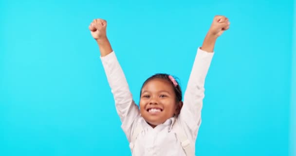 Les enfants, la motivation et la célébration avec une fille sur un fond bleu en studio comme un gagnant joyeux. Portrait, enfants et succès avec une jeune fille posant les bras levés dans la victoire ou la réalisation. - Séquence, vidéo