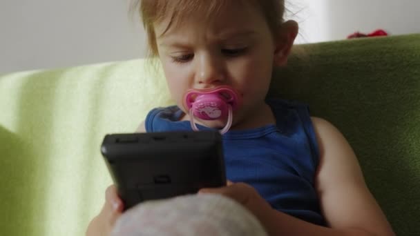 Little baby girl playing with portable videogames console. Kids addiction. - Footage, Video