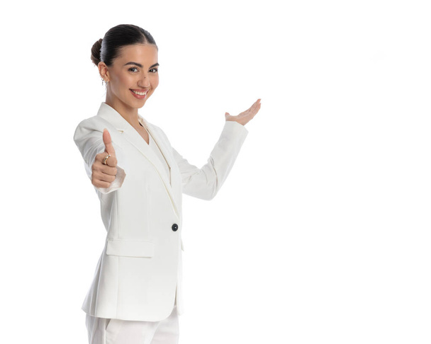 mulher elegante feliz fazendo polegares para cima gesto ao acolher e sorrir na frente do fundo branco - Foto, Imagem