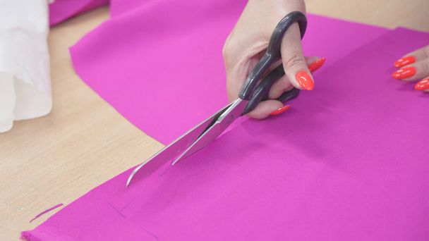 Manos de modista con tijeras en las manos están trabajando en el vestido de costura. - Foto, imagen