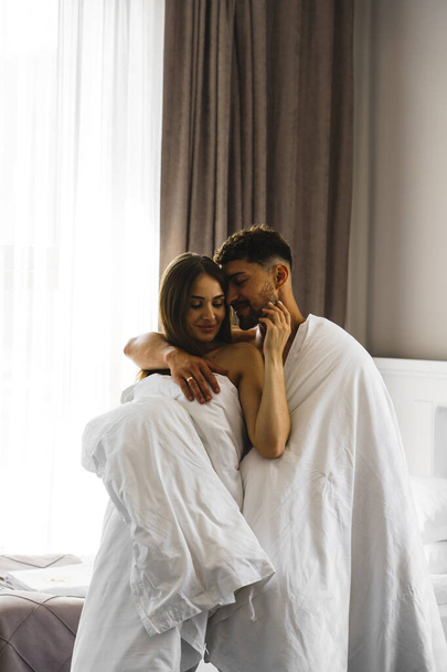 Влюбленная пара, позирующая в одеялах в горном номере отеля. Концепция отдыха в горах - Фото, изображение