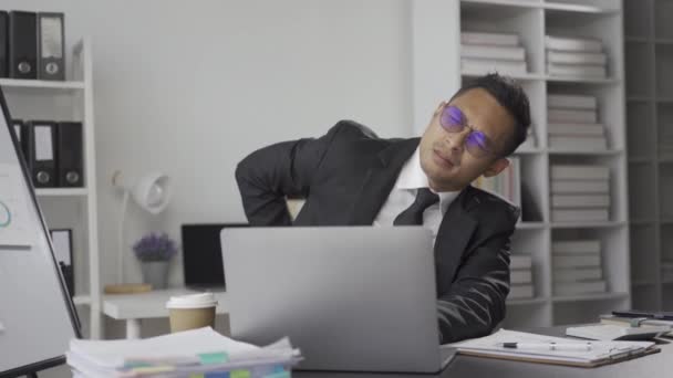 Ázsiai üzletember ellazítja a fájdalmat, fáradt a munkában, fáradt, álmos és unatkozik ül egy asztalnál hosszú ideig, és irodai szindróma férfi kinyújtja a karját, hogy pihenjen, és egy kis szünetet az irodában. - Felvétel, videó