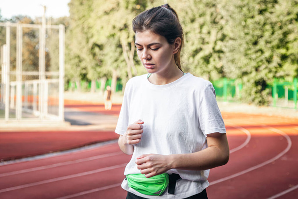 Vonzó fiatal nő sportruházatban kocog a stadionban, nő szabadtéri pályán futás. - Fotó, kép