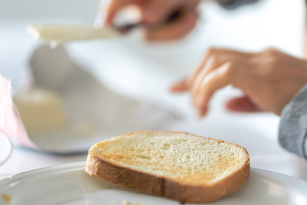 Pedazo de pan de cerca sobre un fondo borroso, concepto de cocina de desayuno, tostadas con mantequilla. - Foto, Imagen