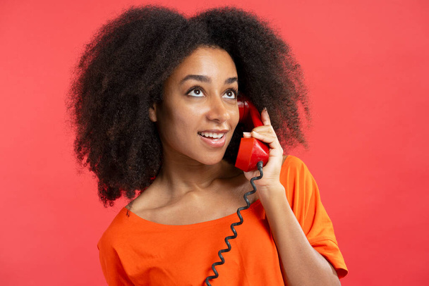 Schöne authentische Afroamerikanerin mit rotem Hörer, Anruf wegschauen isoliert auf rotem Hintergrund, Nahaufnahme. Kommunikationskonzept - Foto, Bild