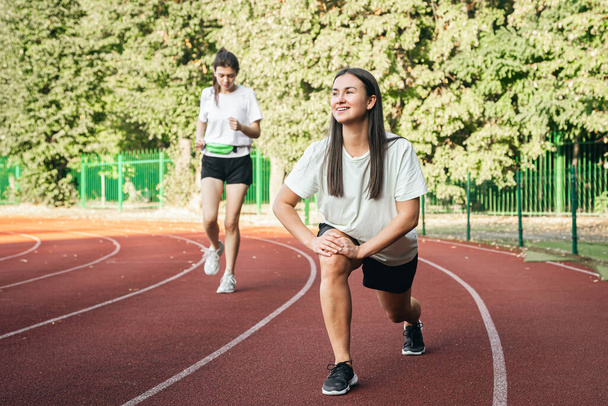 Молодая бегунья в стартовой позиции на беговой дорожке во время тренировки, женщина в спортивной одежде бегает на стадионе. - Фото, изображение