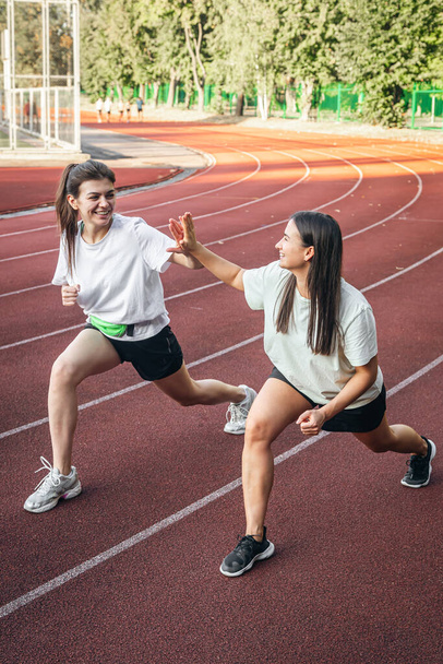 Jovens mulheres atraentes em sportswear jogging no estádio, aquecimento muscular ou bem-estar corporal. - Foto, Imagem