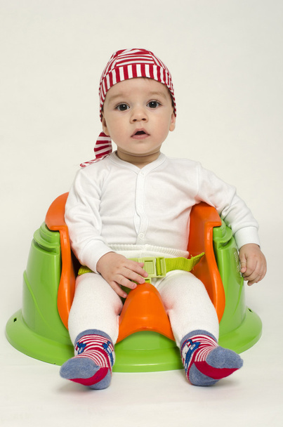 Adorable little boy relaxing in a toy chair ready for his dinner. Baby looking curious with big eyes and open mouth. Playful kid dressed as a pirate - Fotó, kép