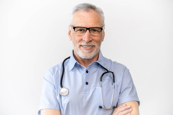 Портрет улыбающегося врача в голубой рубашке со стетоскопом изолирован на белом фоне. Высококвалифицированный специалист с большим опытом работы в кардиологии - Фото, изображение