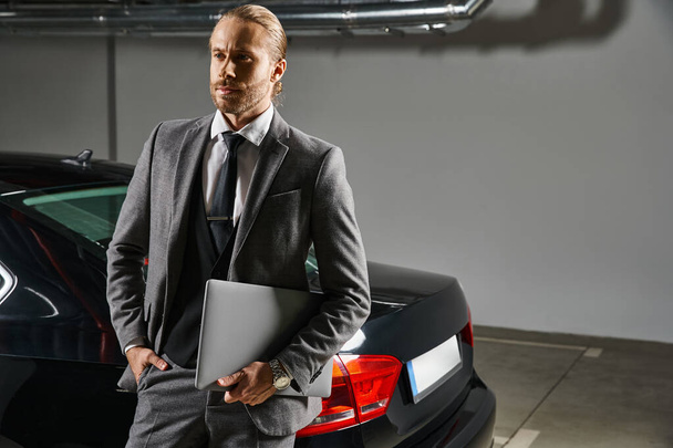 atractivo profesional en traje elegante refinado delante de su coche mirando hacia otro lado, concepto de negocio - Foto, Imagen