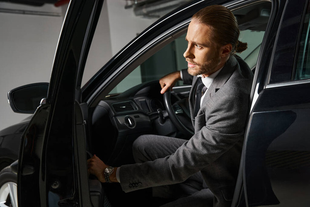 schöner eleganter Mann mit roten Haaren im schicken Anzug, der hinter dem Lenkrad sitzt, Geschäftskonzept - Foto, Bild