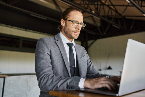 ελκυστική κομψή επαγγελματική με γυαλιά σε έξυπνη κοστούμι εργασίας για το laptop του, επιχειρηματική ιδέα - Φωτογραφία, εικόνα
