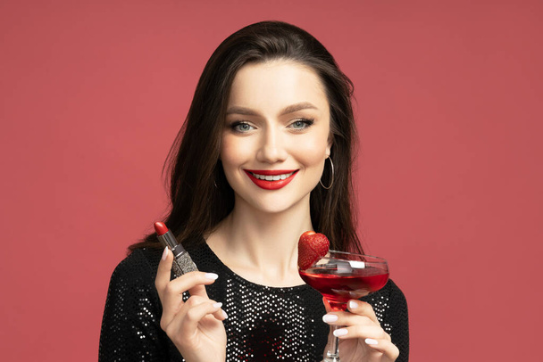 Schöne Brünette mit Lippenstift und einem Cocktail in ihren Händen - Foto, Bild