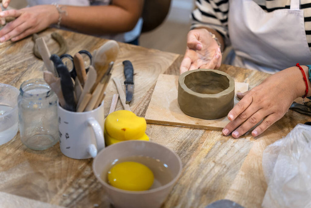 Taller de cerámica. Primer plano de las manos de una joven trabajando arcilla - Foto, Imagen