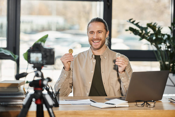 szczęśliwy ambitny biznesmen pokazując bitcoins i nagrywania wideo blog na aparacie cyfrowym w biurze - Zdjęcie, obraz