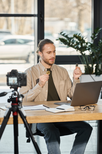 αισιόδοξος επιχειρηματίας που κρατά bitcoins κατά τη διάρκεια της βιντεοκλήσης στο φορητό υπολογιστή μπροστά από την ψηφιακή φωτογραφική μηχανή - Φωτογραφία, εικόνα