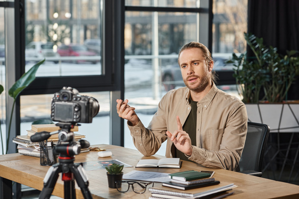seriózní podnikatel mluví a gestikulace před digitální fotoaparát během video blogu v kanceláři - Fotografie, Obrázek