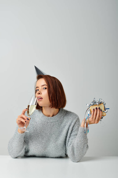 νεαρή γυναίκα με καπέλο κόμμα πίνοντας σαμπάνια και κρατώντας σάντουιτς με tinsel, Καλά Χριστούγεννα - Φωτογραφία, εικόνα