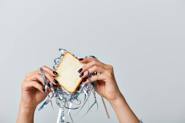 partial view of woman holding sandwich with tinsel on grey backdrop, Happy New Year concept - Photo, Image