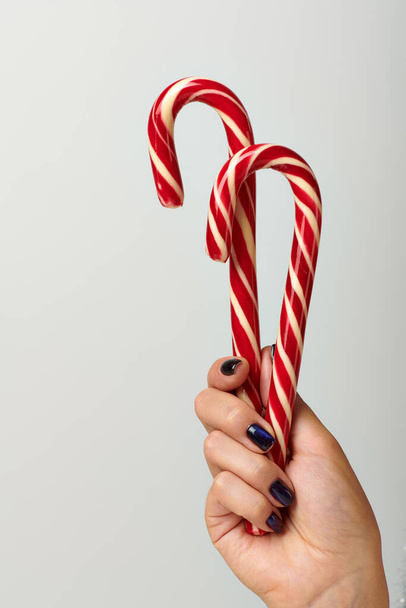 vágott kilátás nő gazdaság spirál piros cukornád szürke alapon, Boldog Karácsonyt koncepció - Fotó, kép