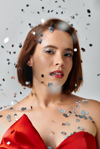 festive makeup, young woman with short hair and sparkling eye shadow looking at camera on grey - Photo, Image