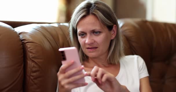 Vrouw op de bank leest vanaf smartphone scherm, close-up. Het concept van gedragsverslaving, rust met de telefoon - Video